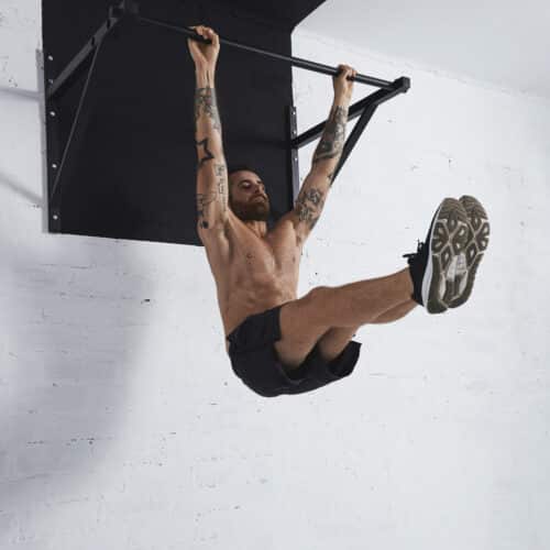 Homme faisant des tractions dans une salle blanche.