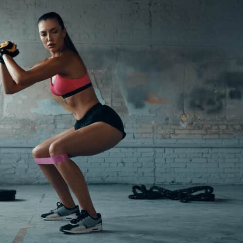 Femme faisant exercice squat avec élastique fitness.