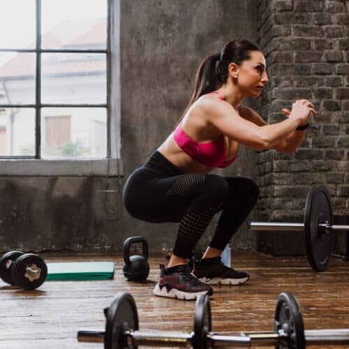 Femme faisant des squats en salle de sport.