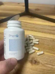 Flacon ouvert de gélules PhenQ sur une table.