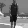 Homme debout devant plage en noir et blanc.