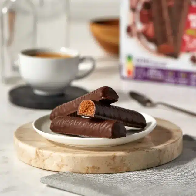 Biscuits enrobés de chocolat, café en arrière-plan.