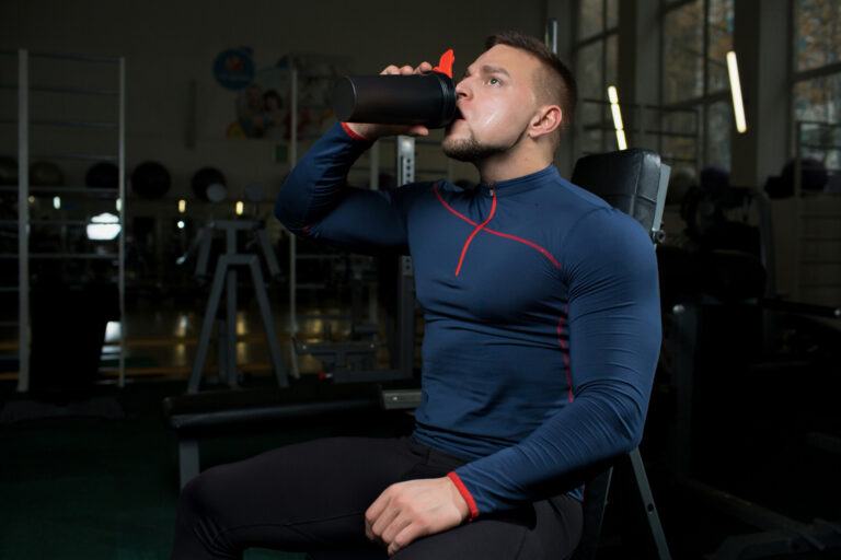 Homme buvant shaker à la salle de sport.