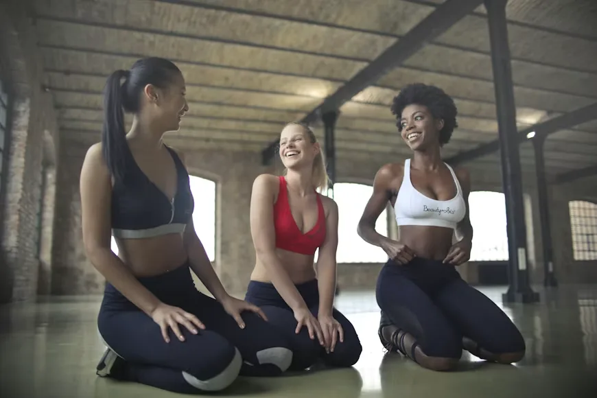 Trois sportives assises au sol dans une salle d'entraînement